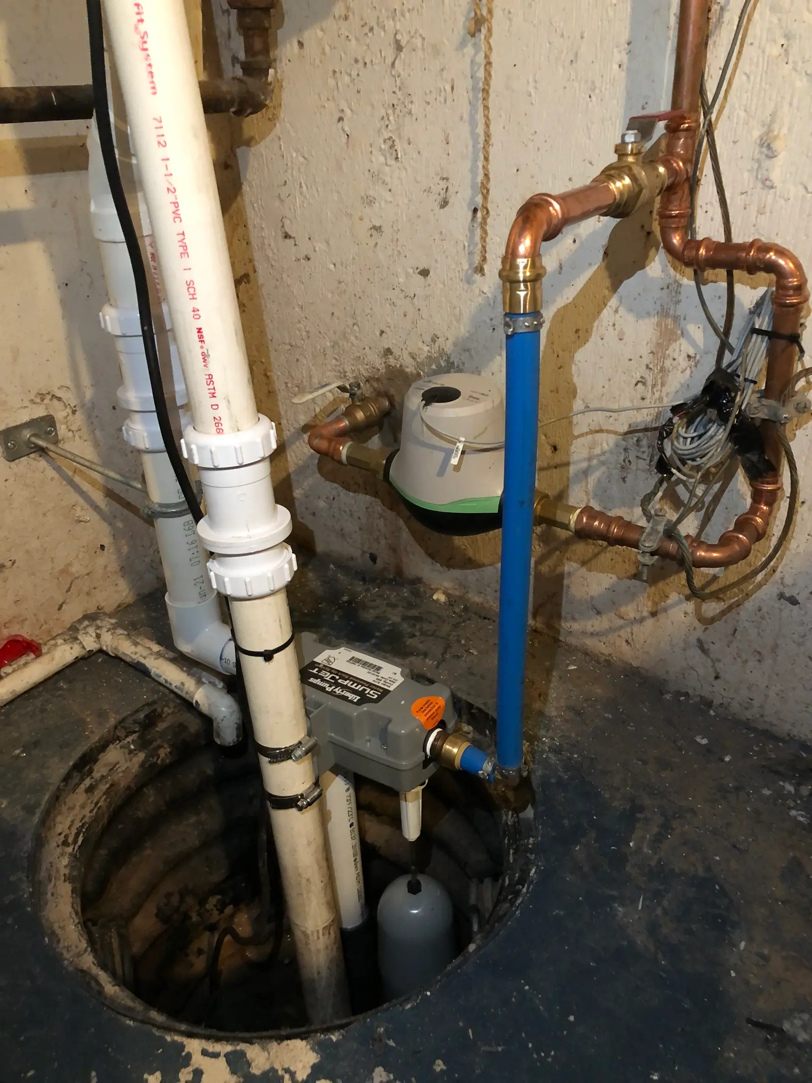 A basement sump pump, pit, and discharge piping. Shown on the homepage for Fort Wayne, IN.